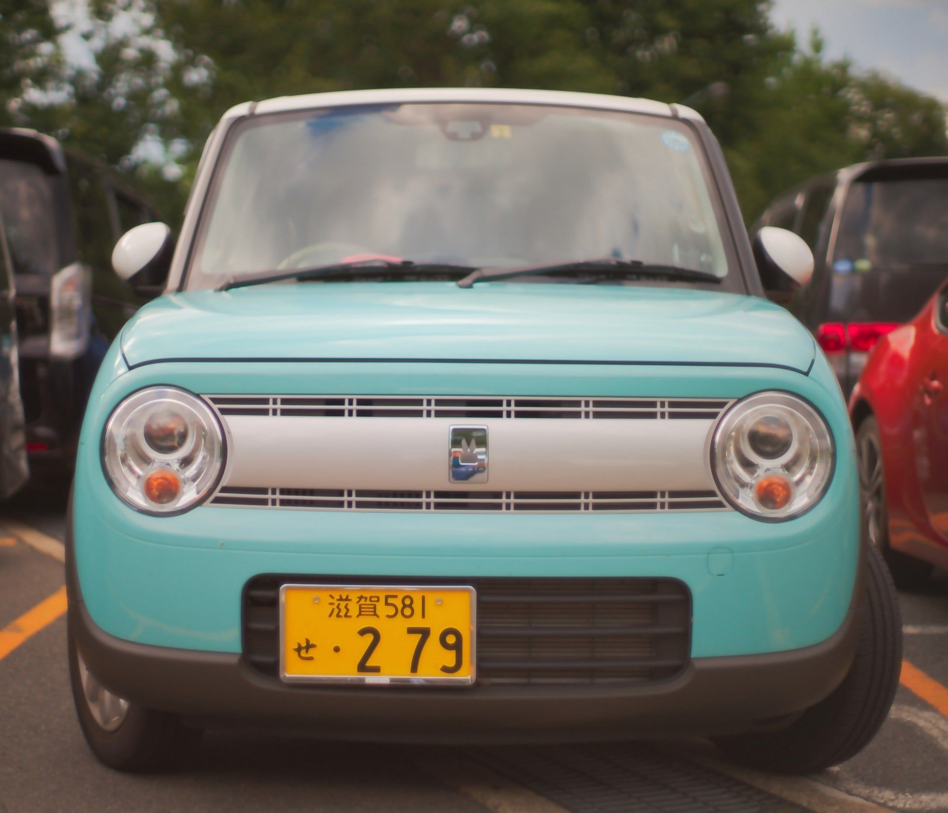 Une voiture japonaise bleue turquoise faisant vue de face.